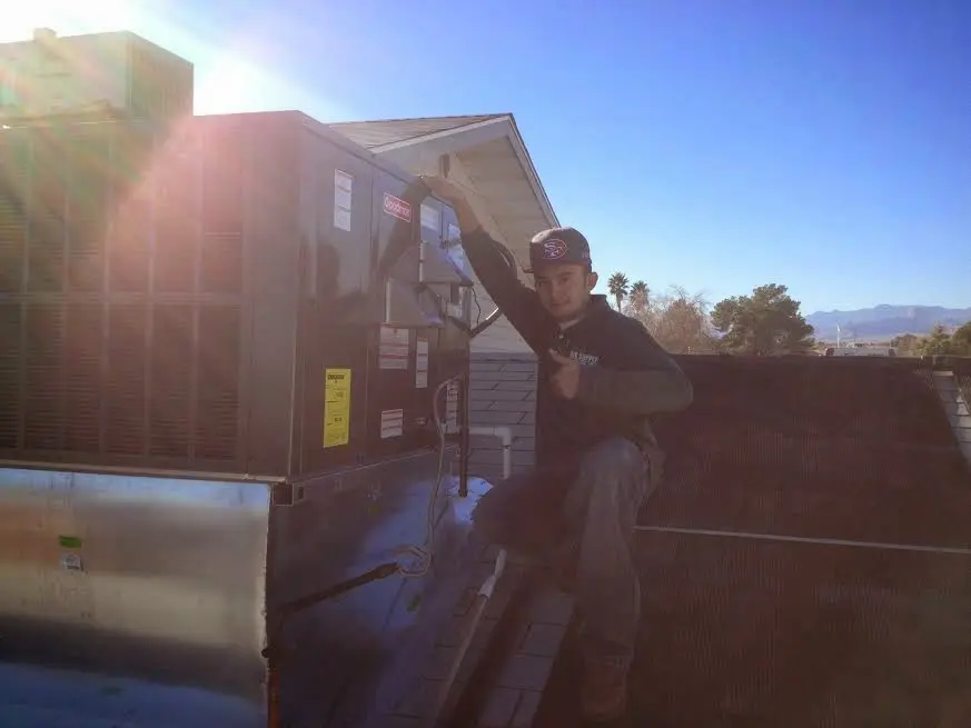 HVAC technician performing Air Duct Cleaning on a rooftop unit in Pitman